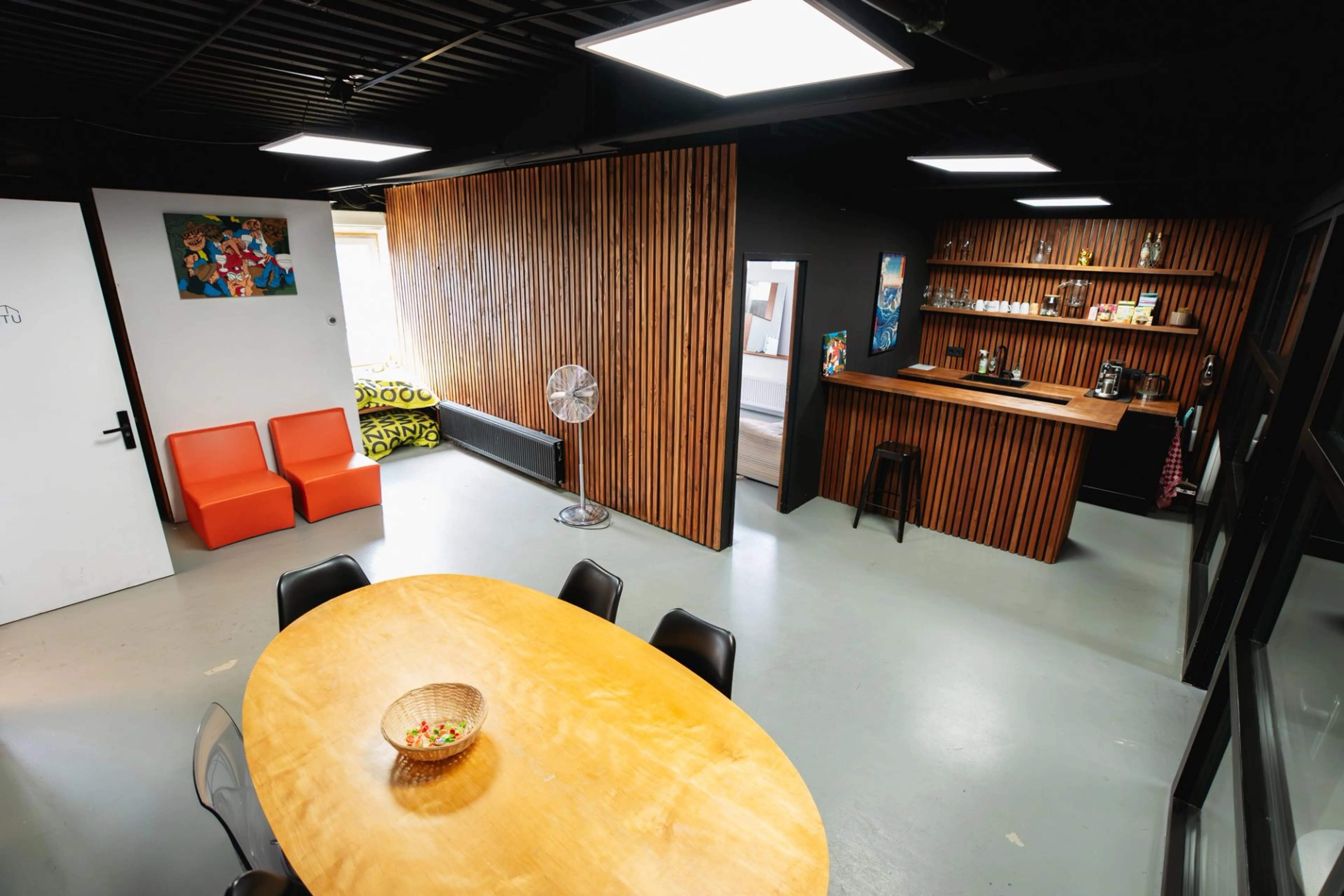 Client lounge en pantry bij De Stu Amsterdam, professionele foto- en filmstudio met vergadertafel, koffiebar en faciliteiten voor productieteams.