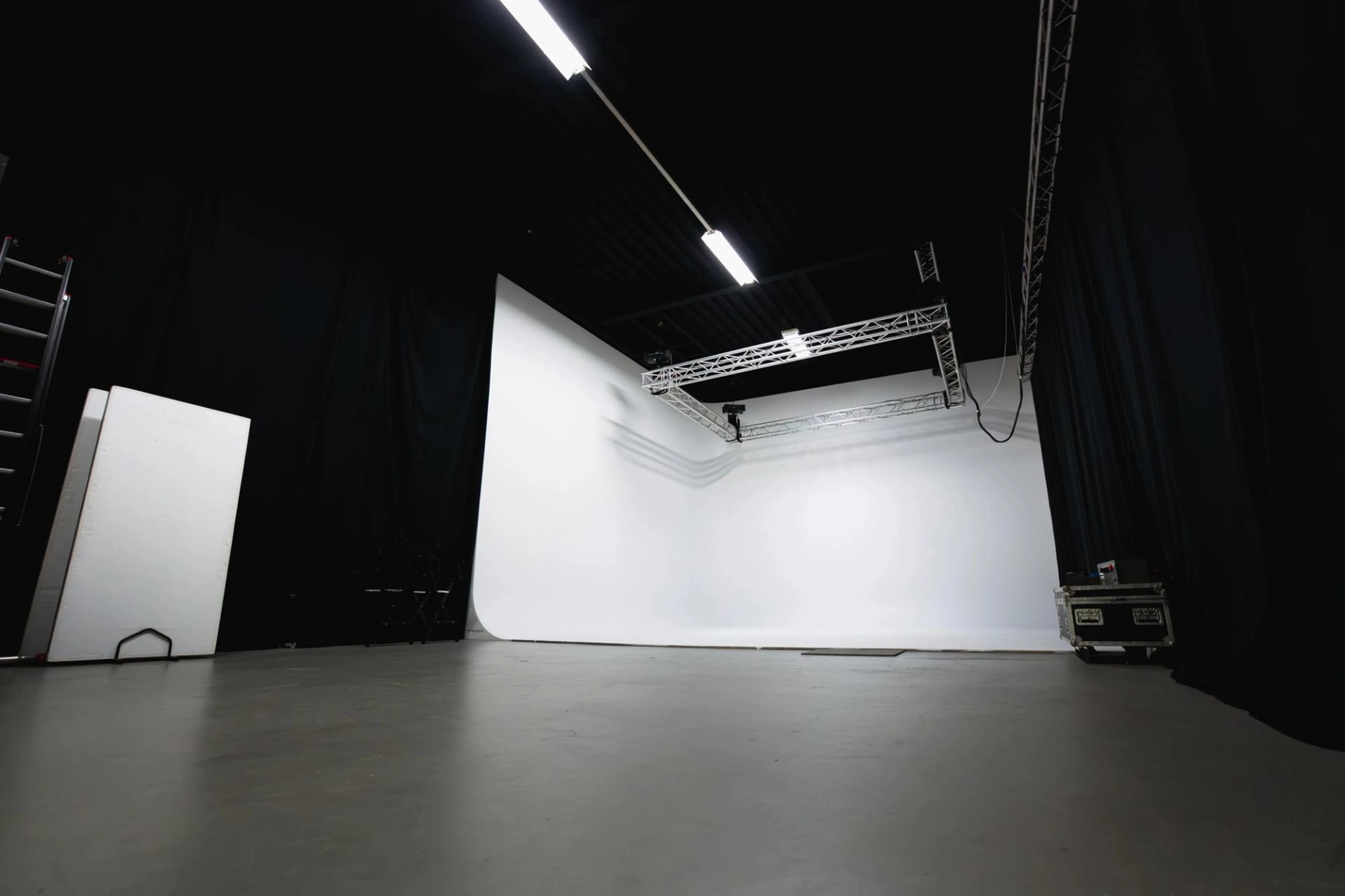 Grote cyclorama studio bij De Stu Amsterdam met witte infinity wall, gemotoriseerd truss-systeem en professionele faciliteiten voor foto- en videoproducties.