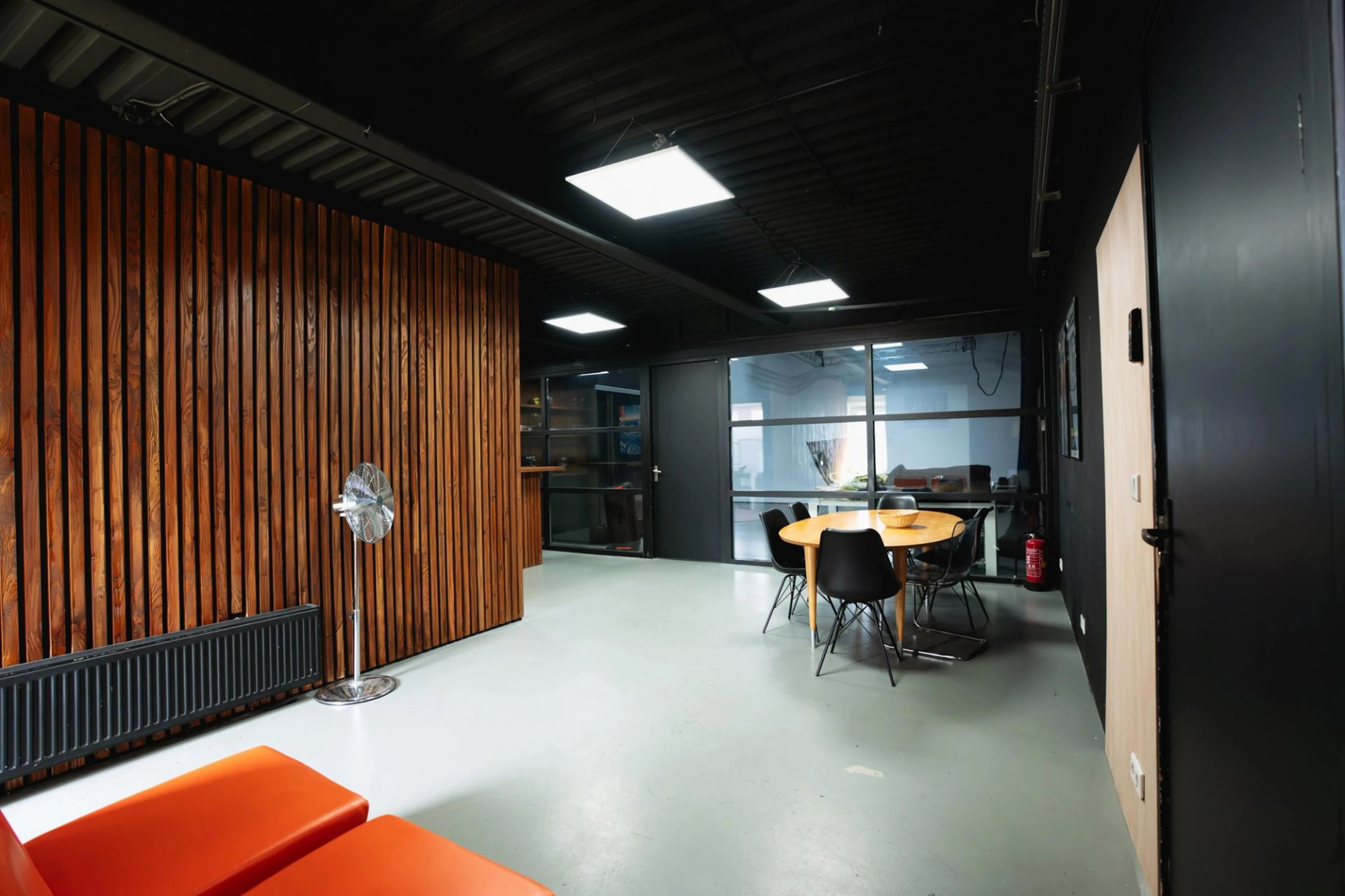 Client lounge en productieruimte bij De Stu Amsterdam met vergadertafel, zitgedeelte en uitzicht op de fotostudio.
